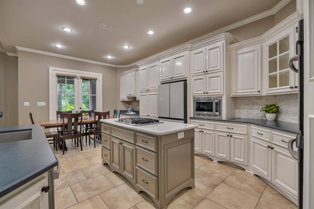 1915 Stonegate Valley Drive, Tyler, TX 75703 Kitchen featuring a central island with a gas cooktop, perimeter cabinetry with dark countertops, stainless steel appliances including built-in microwave, and tile flooring