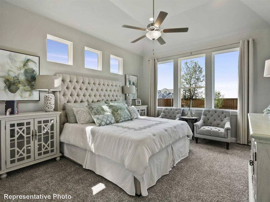 1317 Staffords Point Lane, Anna, TX 75409 Spacious bedroom featuring light gray wall paint, multiple windows, plush carpet flooring, a ceiling fan with integrated lighting, and a tray ceiling