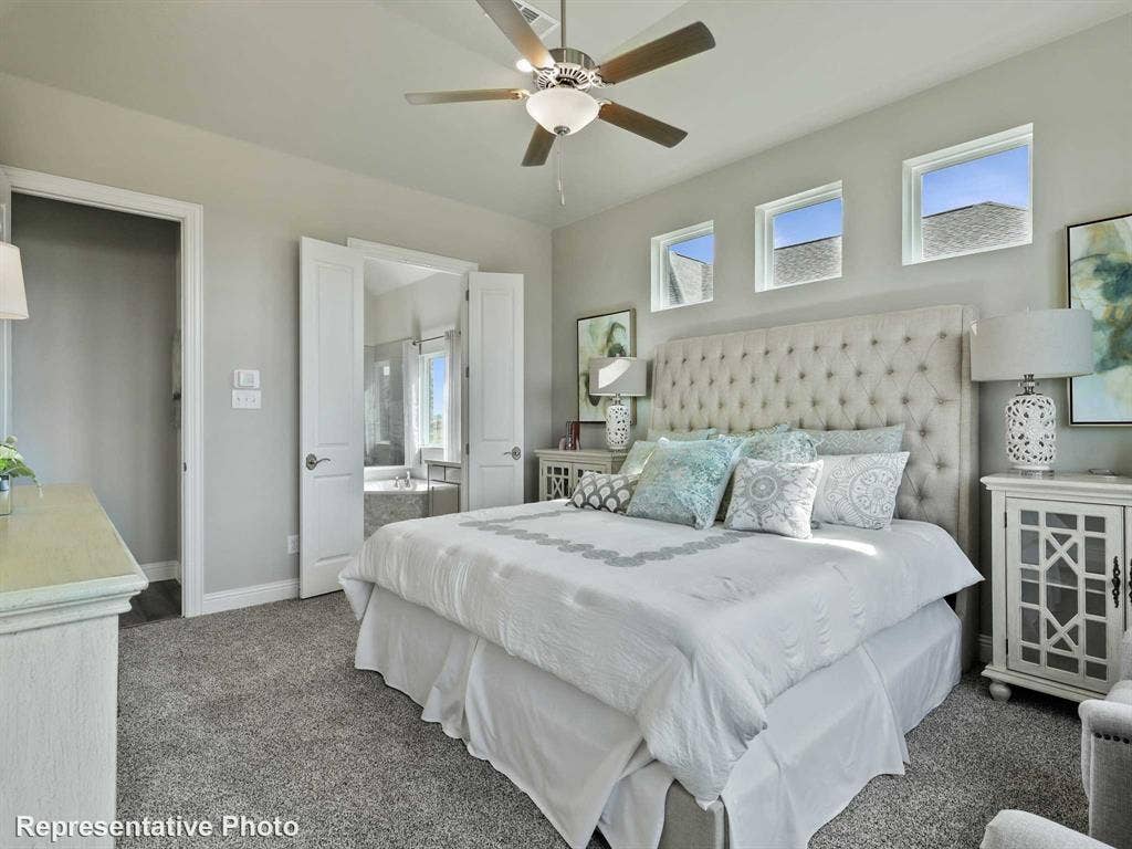 1317 Staffords Point Lane, Anna, TX 75409 Carpeted bedroom featuring a ceiling fan with integrated lighting, three transom windows, and double doors opening to an ensuite bathroom with a built-in tub