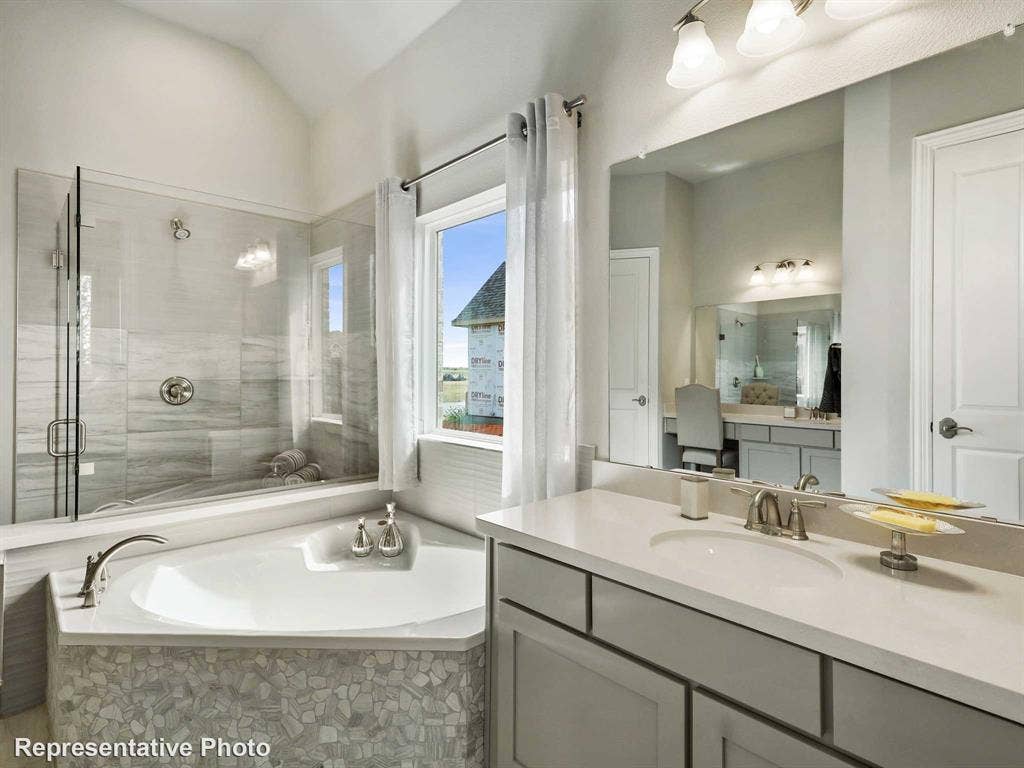 1317 Staffords Point Lane, Anna, TX 75409 Spacious bathroom featuring a corner soaking tub with mosaic tile surround, a glass-enclosed shower with subway tile, a vanity with an undermount sink and ample counter space, and a large mirror