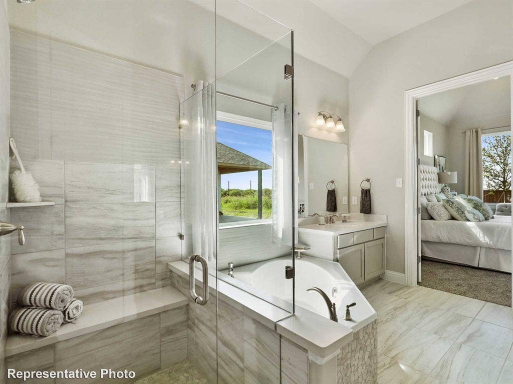 1317 Staffords Point Lane, Anna, TX 75409 Bathroom featuring a glass-enclosed shower with a built-in bench, a separate soaking tub, and a dual vanity with undermount sinks