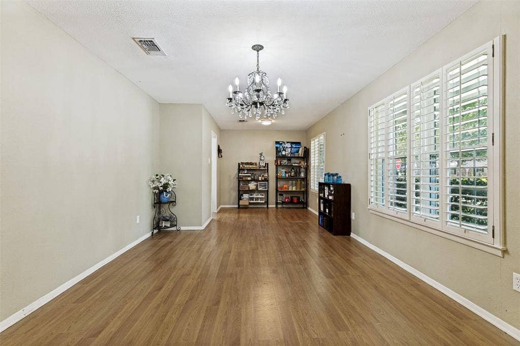 1121 W Redbud Drive, Hurst, TX 76053 Dining room featuring wood flooring, crystal chandelier, and white wood shutters