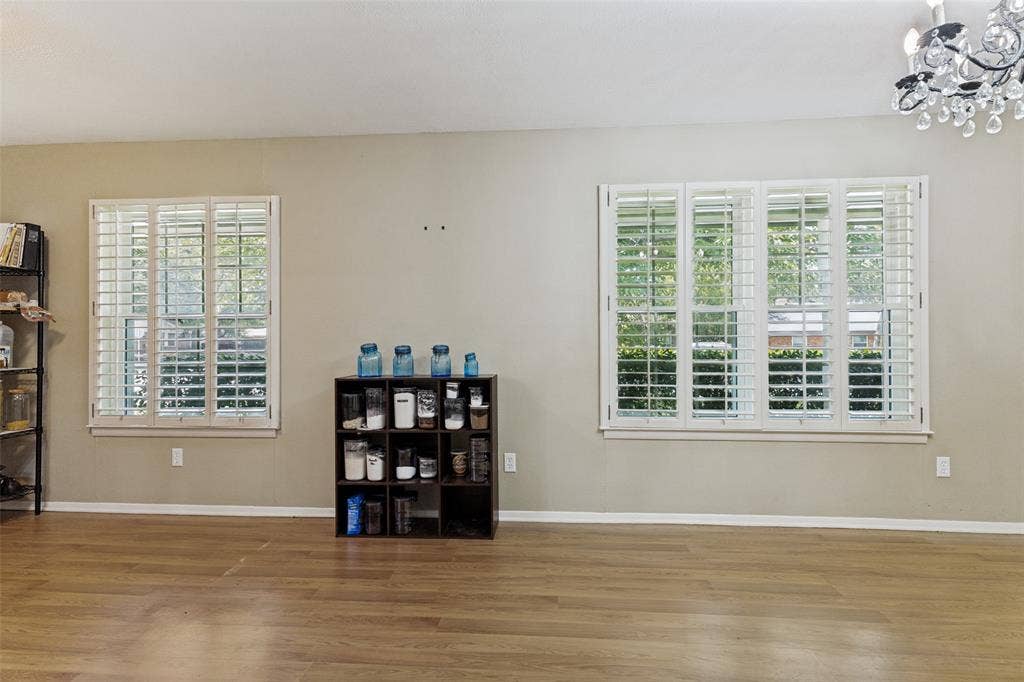 1121 W Redbud Drive, Hurst, TX 76053 Dining room featuring wood flooring, crystal chandelier, and white wood shutters