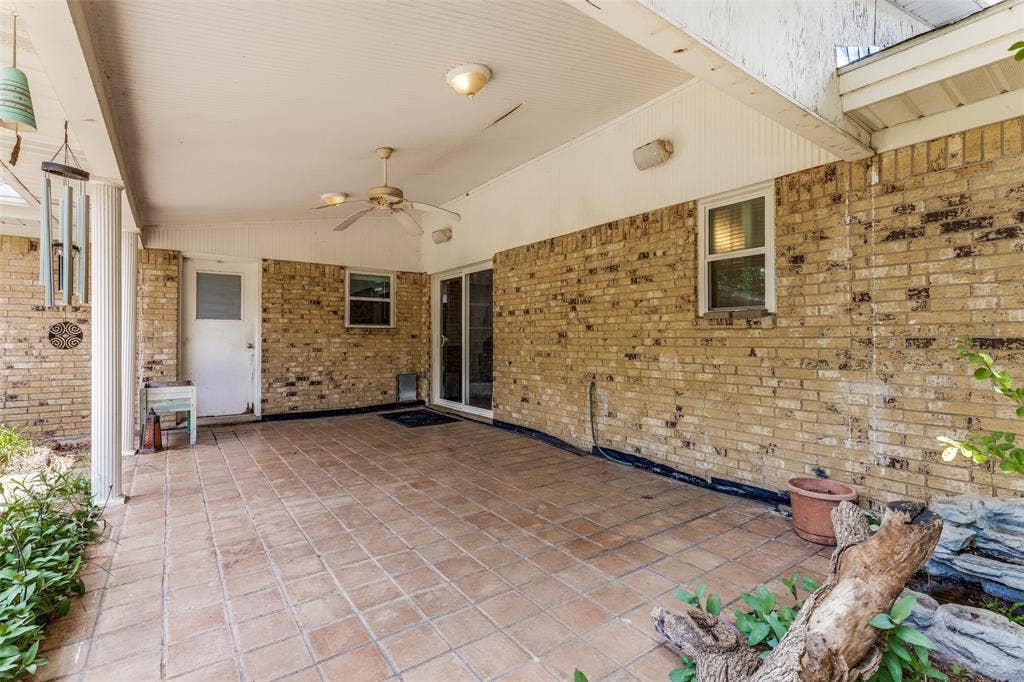 1121 W Redbud Drive, Hurst, TX 76053 Expansive covered patio featuring terracotta-style tile flooring, a ceiling fan, and a light-colored brick exterior