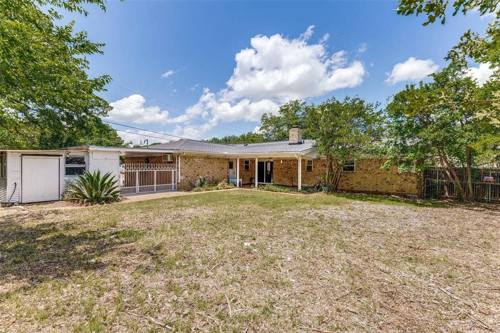 1121 W Redbud Drive, Hurst, TX 76053 Brick exterior home featuring a covered patio, a detached shed, and mature perimeter trees