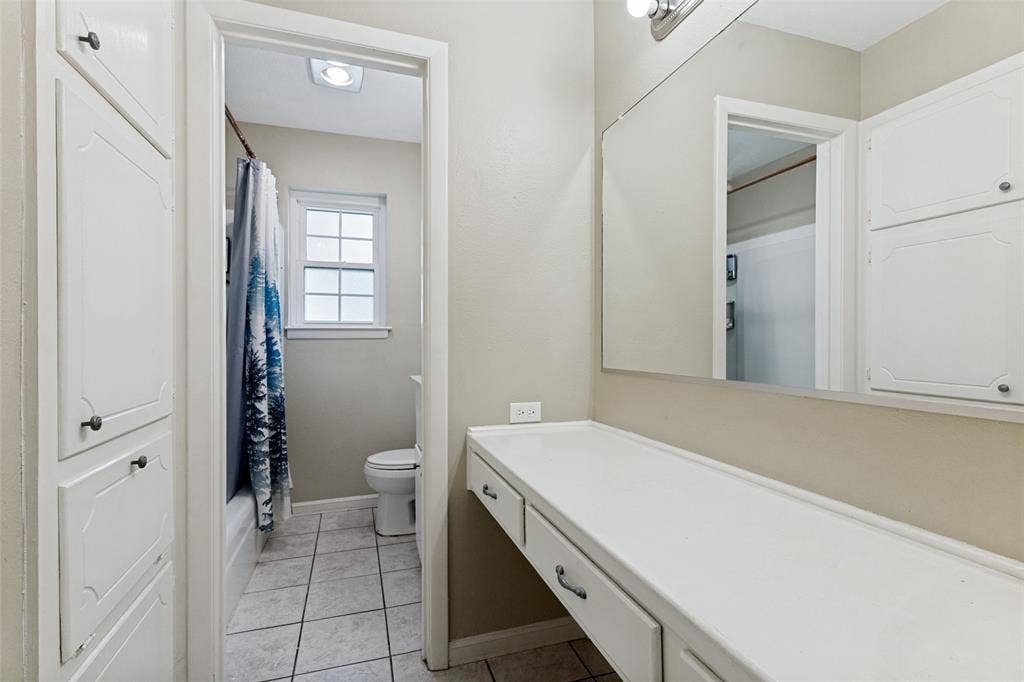 1121 W Redbud Drive, Hurst, TX 76053 Bathroom vanity featuring a large mirror, built-in cabinetry, and integrated countertop with storage drawers