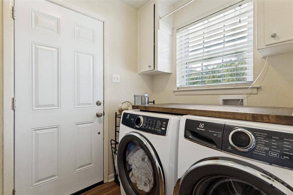 1121 W Redbud Drive, Hurst, TX 76053 Dedicated laundry area featuring a wood-finish countertop, upper cabinetry, and a window with blinds