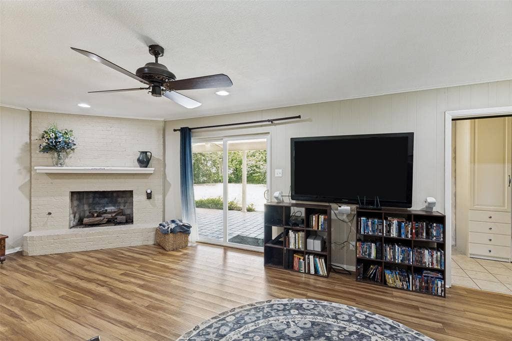 1121 W Redbud Drive, Hurst, TX 76053 Spacious interior featuring wood-finish flooring and a corner brick fireplace with a mantle