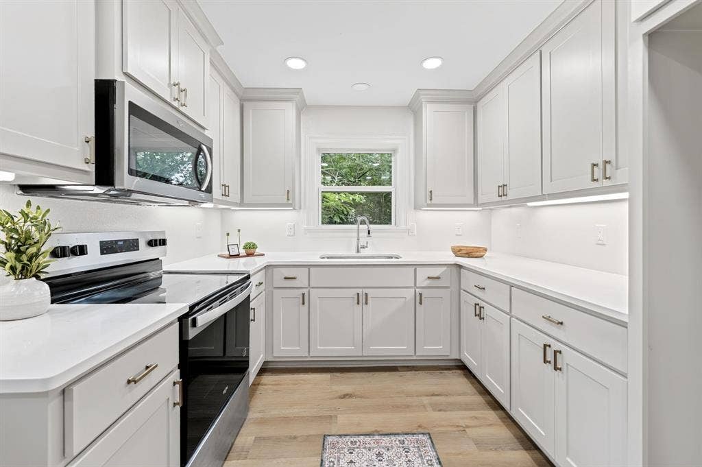 608 Bunny Rabbit Road, Athens, TX 75751 Bright kitchen featuring white shaker cabinetry, stainless steel appliances, white countertops, a window over the sink, and wood-finish flooring