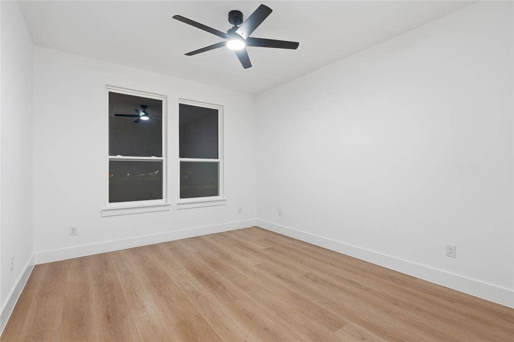 2212 Marburg Street, Dallas, TX 75215 Bright room featuring two large windows, wood-finish flooring, white baseboards, and a modern ceiling fan with integrated lighting