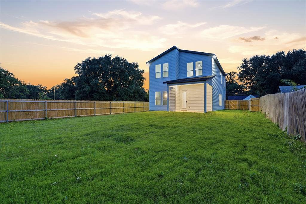 2212 Marburg Street, Dallas, TX 75215 Expansive backyard featuring a large green lawn, full perimeter privacy fencing, and a covered patio area