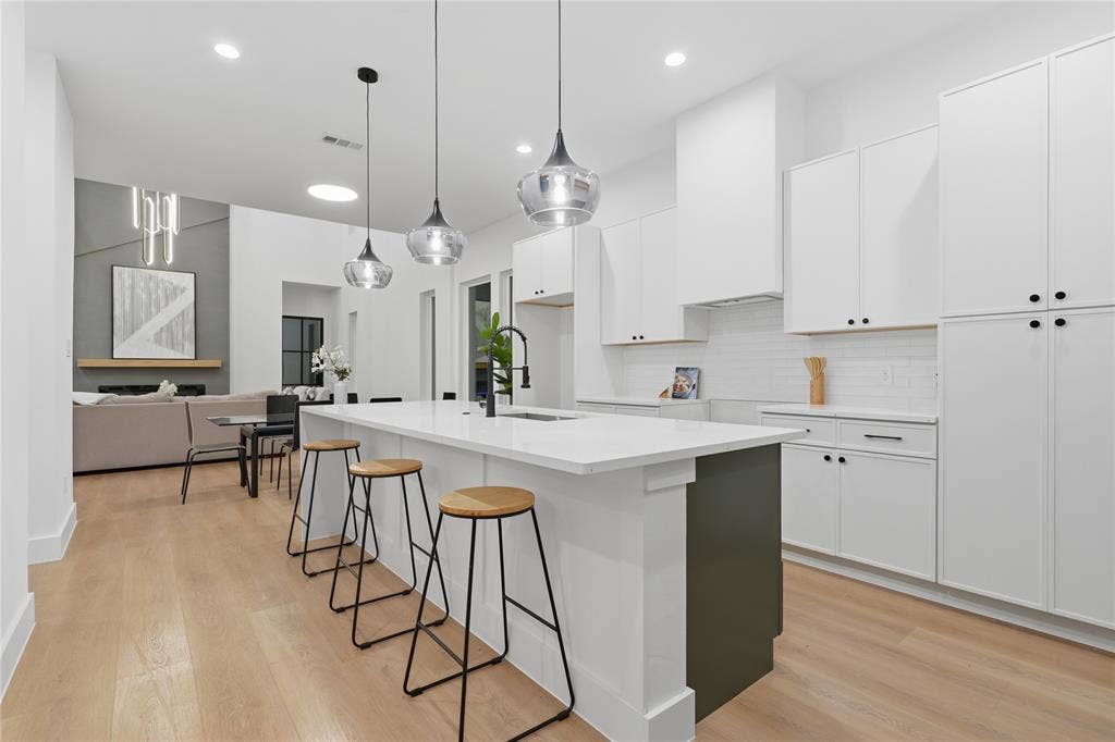 2212 Marburg Street, Dallas, TX 75215 Open-concept kitchen featuring an oversized island with seating, white shaker cabinetry, white subway tile backsplash, and wood-finish flooring