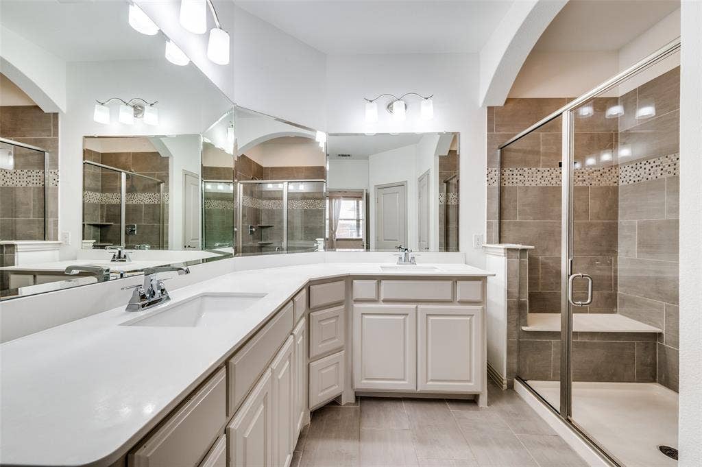7424 Mitchell Drive, McKinney, TX 75070 Bathroom with double vanity, large mirror, and stall shower, offering a spacious primary or secondary bath setup with extra counter space and storage, appealing to buyers who want a McKinney Texas townhouse with updated bathrooms, double sinks, and convenient layout in a well located Collin County community