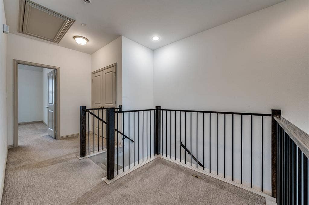 7424 Mitchell Drive, McKinney, TX 75070 Upstairs hallway with landing, light colored carpet, iron railing, recessed lighting, and access to multiple rooms, connecting bedrooms and living spaces in this McKinney TX townhome for sale and showcasing the open second level layout in a Collin County two story townhouse with functional design.