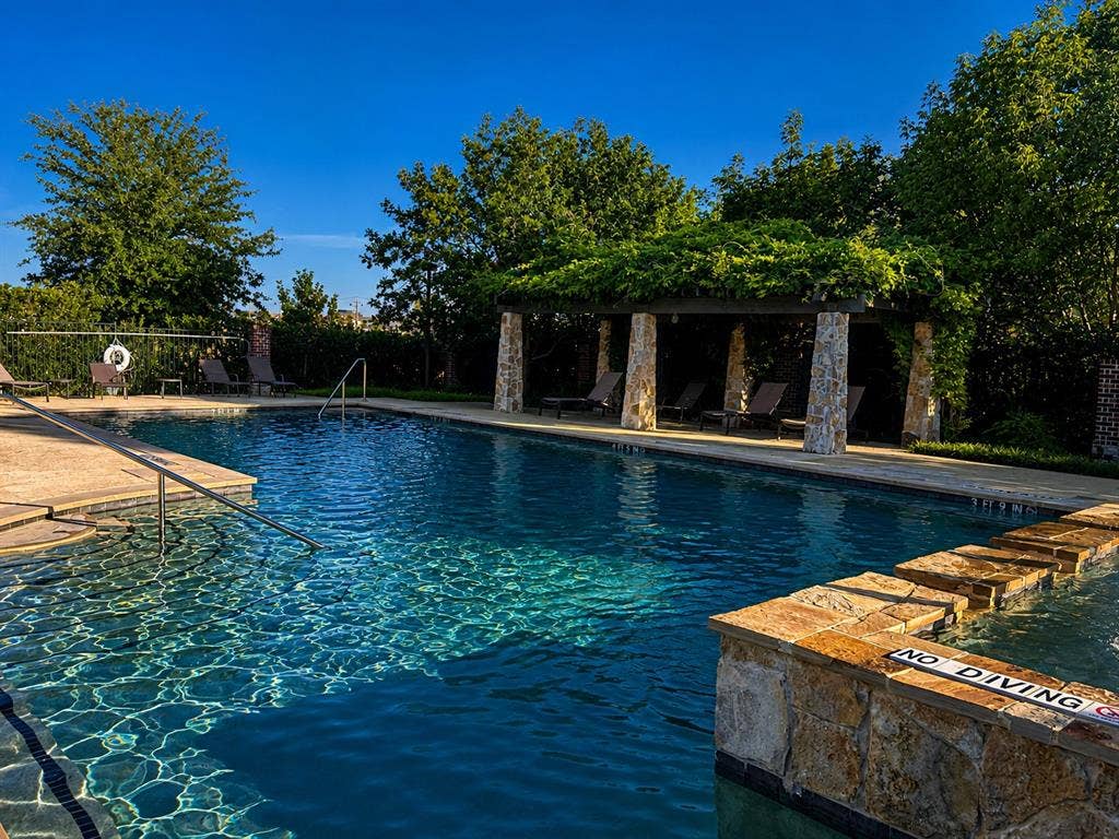 7424 Mitchell Drive, McKinney, TX 75070 Outdoor swimming pool featuring stone coping, a stone-clad hot tub with step entry, and a covered pergola