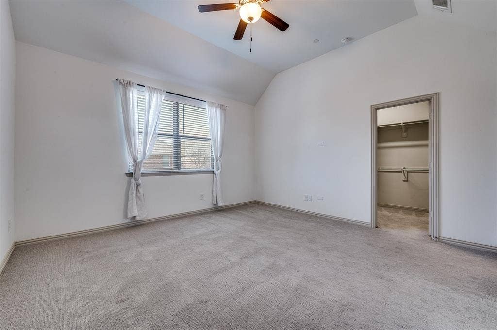 7424 Mitchell Drive, McKinney, TX 75070 Unfurnished bedroom with spacious closet, lofted ceiling, light colored carpet, and ceiling fan, creating a comfortable secondary bedroom option for family members, guests, or roommates in this McKinney Texas townhome convenient to area schools, neighborhood parks, shopping centers, and everyday amenities in North Texas.