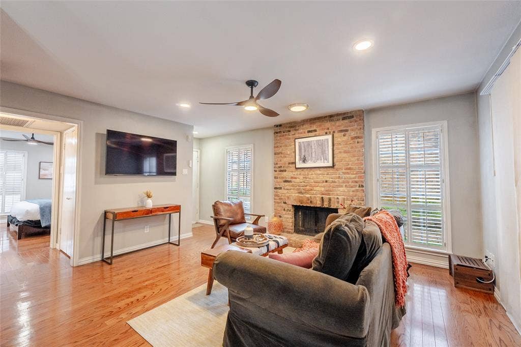15221 Berry Trail, #1201, Dallas, TX 75248 Living area featuring polished wood-finish flooring, a brick fireplace with a dark firebox, and recessed lighting