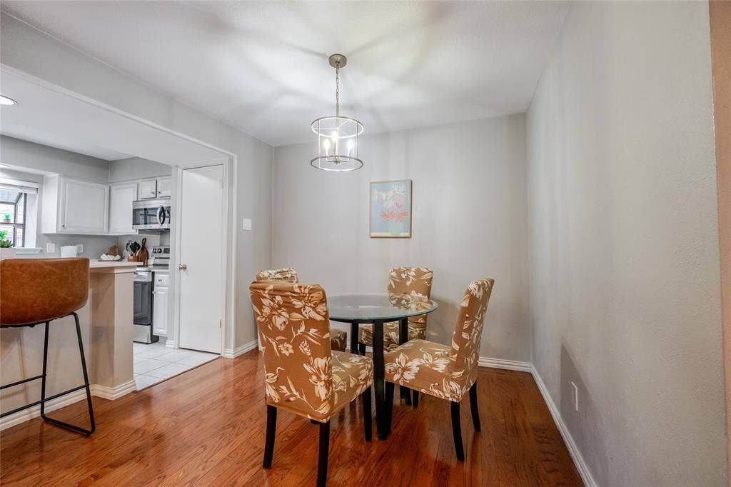 15221 Berry Trail, #1201, Dallas, TX 75248 Dining area featuring wood-finish flooring, a contemporary chandelier, and a framed art piece
