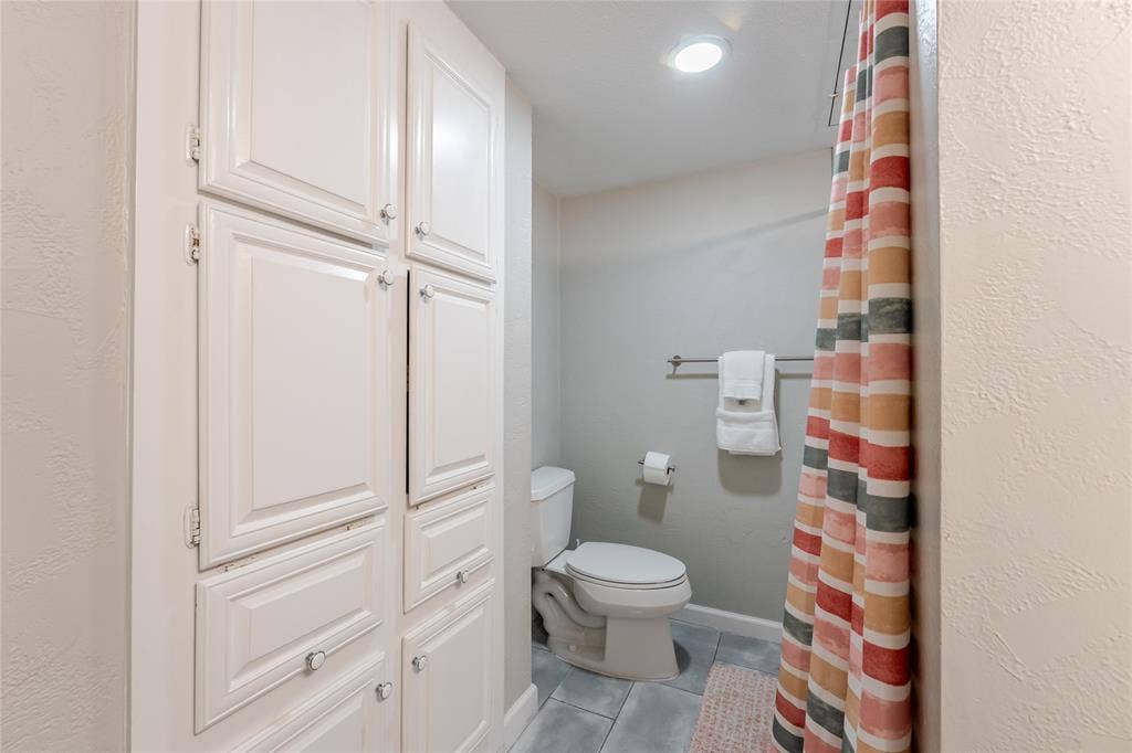 15221 Berry Trail, #1201, Dallas, TX 75248 Built-in cabinetry with paneled doors and clear knobs, gray wall paint, recessed lighting, and tile flooring
