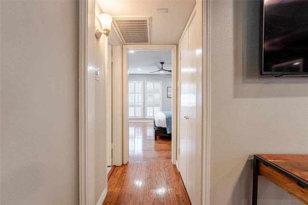15221 Berry Trail, #1201, Dallas, TX 75248 Hallway featuring wood-finish flooring, white walls, and a wall-mounted sconce