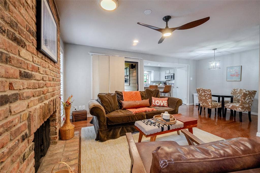 15221 Berry Trail, #1201, Dallas, TX 75248 Spacious living area featuring a brick fireplace, wood-finish flooring, and a contemporary ceiling fan