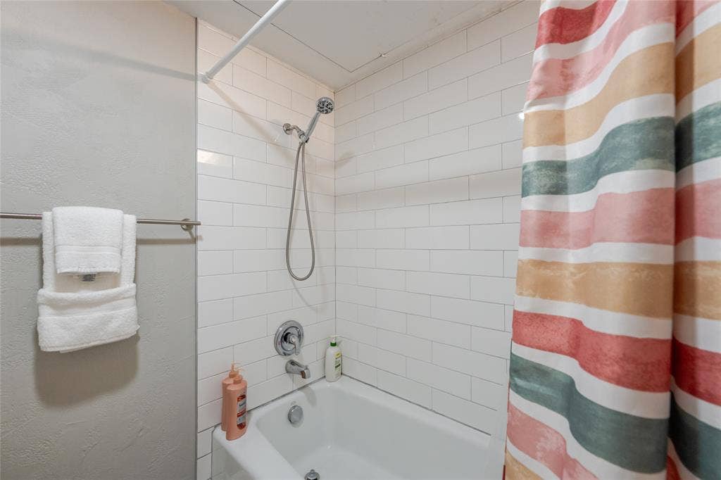 15221 Berry Trail, #1201, Dallas, TX 75248 Bathtub and shower combination featuring subway tile surround, chrome fixtures, and a curved shower rod