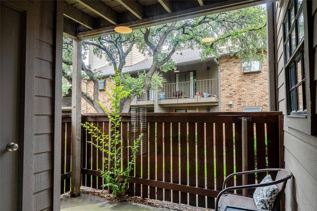 15221 Berry Trail, #1201, Dallas, TX 75248 Covered patio featuring a slatted wood privacy fence, concrete flooring, and a ceiling-mounted light fixture