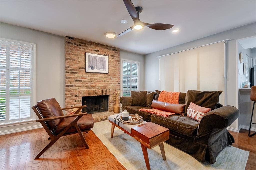 15221 Berry Trail, #1201, Dallas, TX 75248 Living area featuring a brick fireplace, hardwood flooring, and white plantation shutters on dual windows