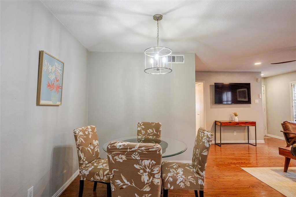 15221 Berry Trail, #1201, Dallas, TX 75248 Open concept dining area featuring a contemporary chandelier, hardwood flooring, and light-toned walls