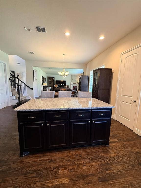 7310 Venice Drive, #4, Grand Prairie, TX 75054 Kitchen island featuring dark wood cabinetry, a light-colored speckled countertop, and integrated seating
