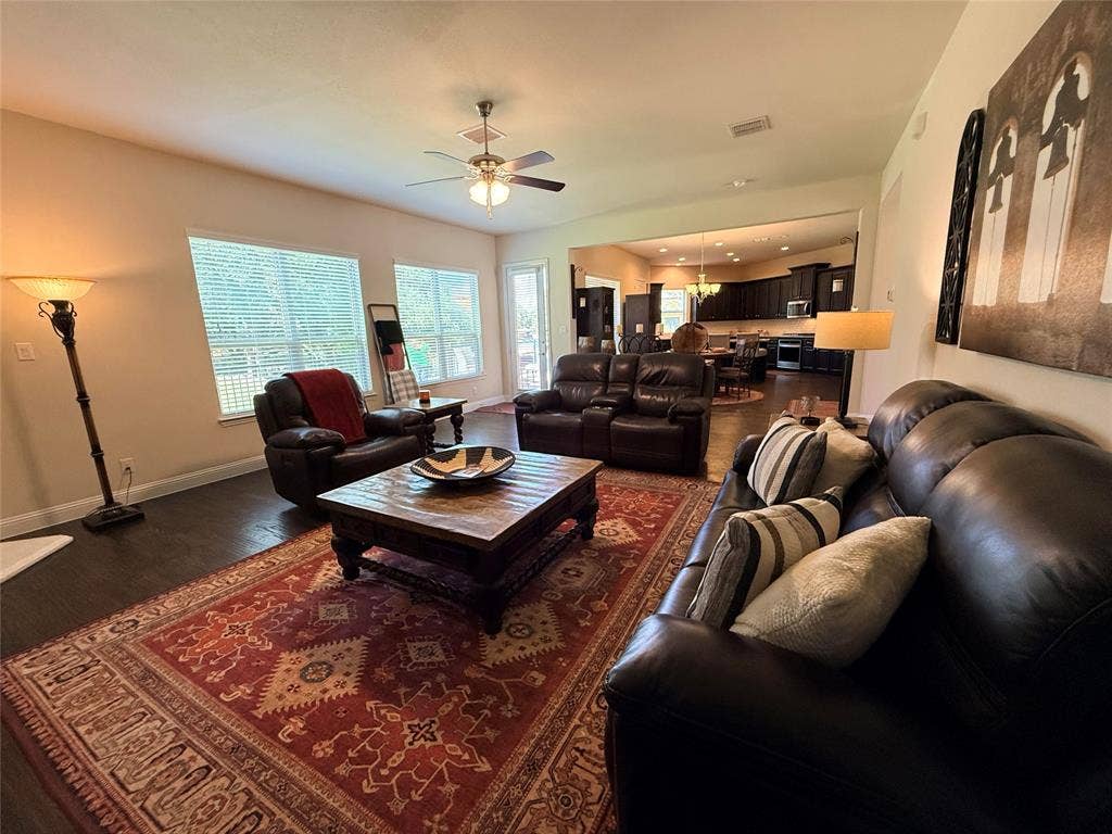 7310 Venice Drive, #4, Grand Prairie, TX 75054 Spacious living area featuring wood-finish flooring, multiple windows with blinds, a ceiling fan, and an open layout to the kitchen