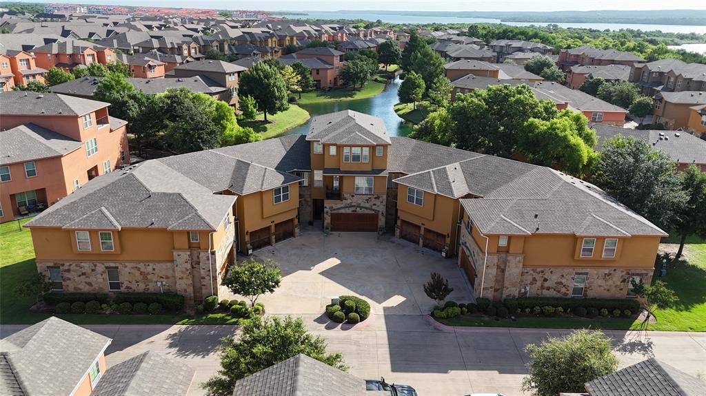 7310 Venice Drive, #4, Grand Prairie, TX 75054 Multi-level residential complex featuring a central courtyard, stone and stucco exterior finishes, individual garage doors, and a paved driveway