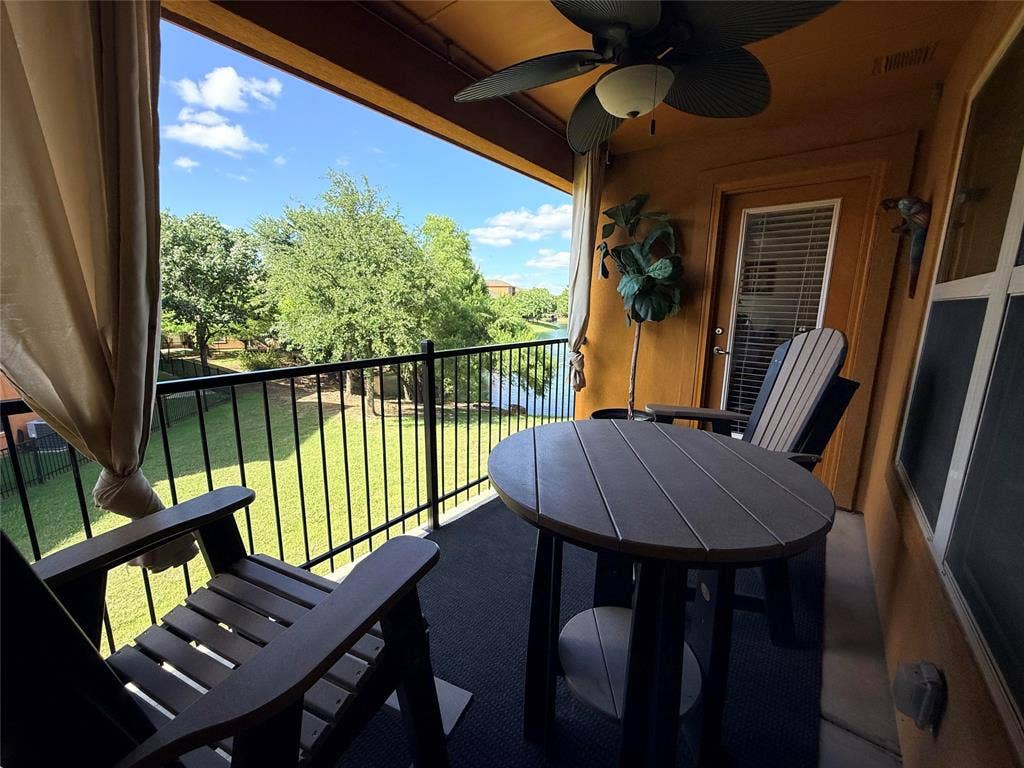 7310 Venice Drive, #4, Grand Prairie, TX 75054 Covered balcony featuring a ceiling fan, black iron railing, and a view of green space and a body of water
