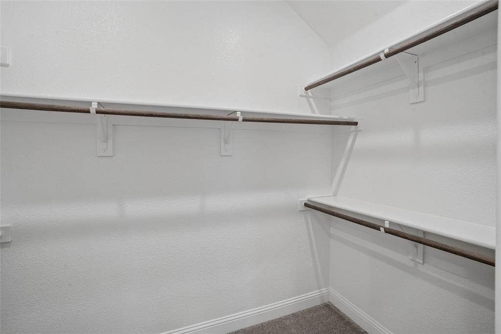 317 Fire Rock Drive, Royse City, TX 75189 White-painted closet interior featuring multiple wooden hanging rods, white shelving, and white baseboards