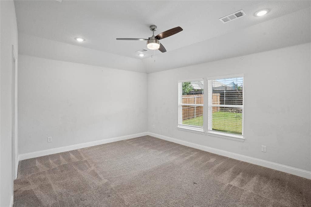317 Fire Rock Drive, Royse City, TX 75189 Spacious room featuring neutral carpeting, a ceiling fan with integrated lighting, recessed lighting, and a dual-pane window overlooking a fenced yard