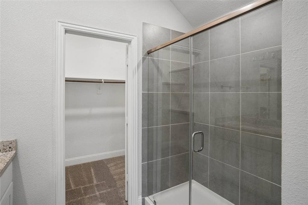317 Fire Rock Drive, Royse City, TX 75189 Glass-enclosed shower with gray square tile surround and bronze-finish framing