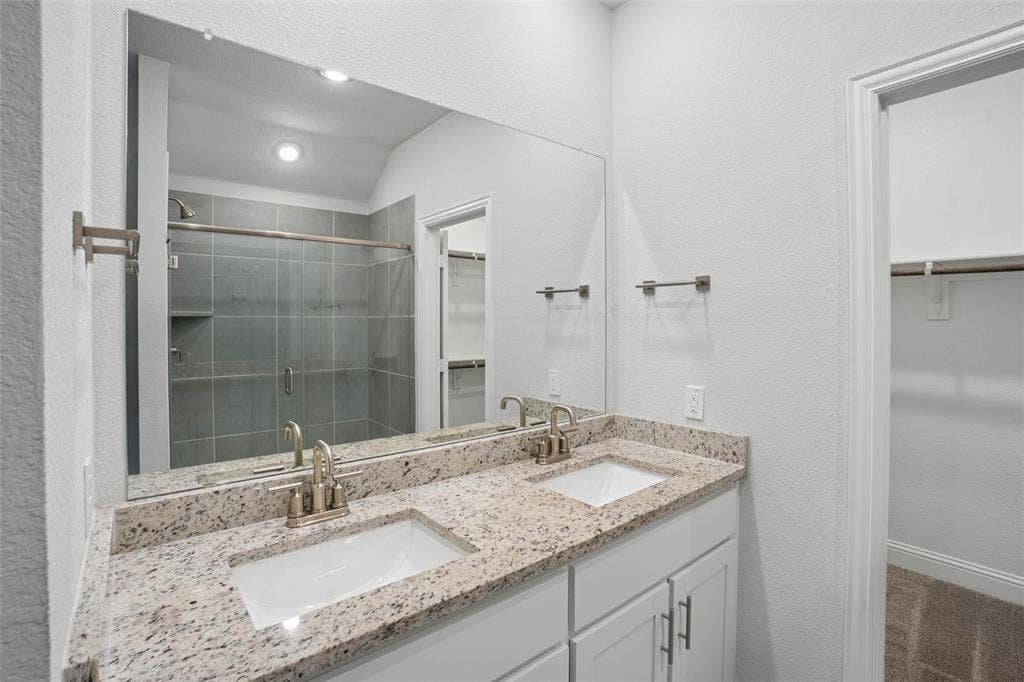 317 Fire Rock Drive, Royse City, TX 75189 Dual vanity with granite countertop, integrated sinks, brushed nickel fixtures, and white cabinetry