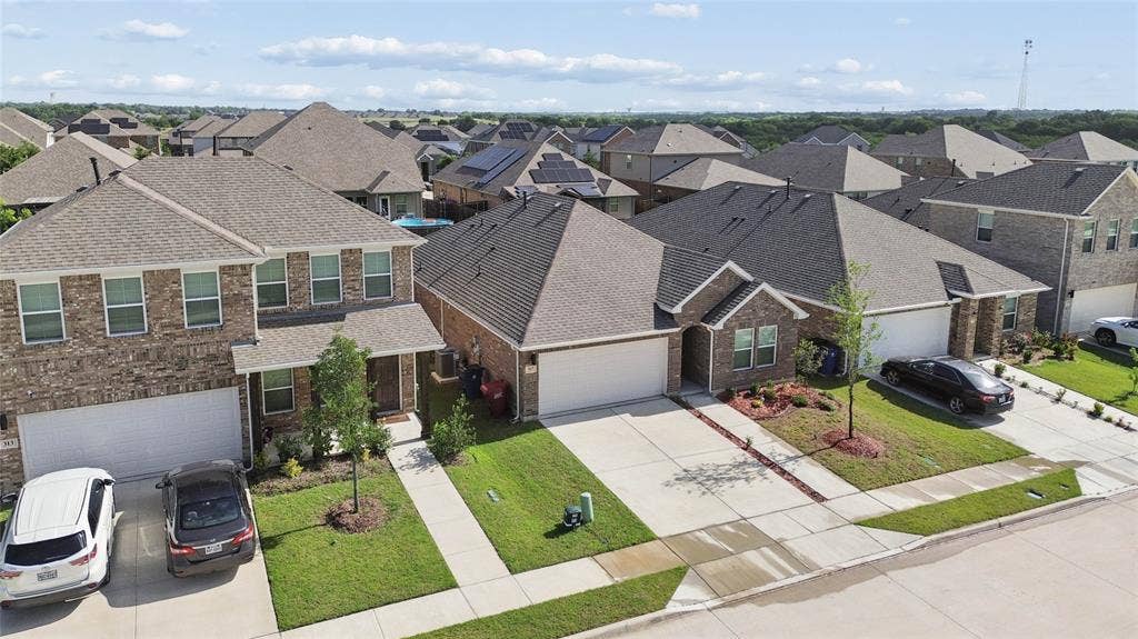317 Fire Rock Drive, Royse City, TX 75189 Contemporary brick residence featuring an attached two-car garage, manicured lawn, paved driveway, and established landscaping
