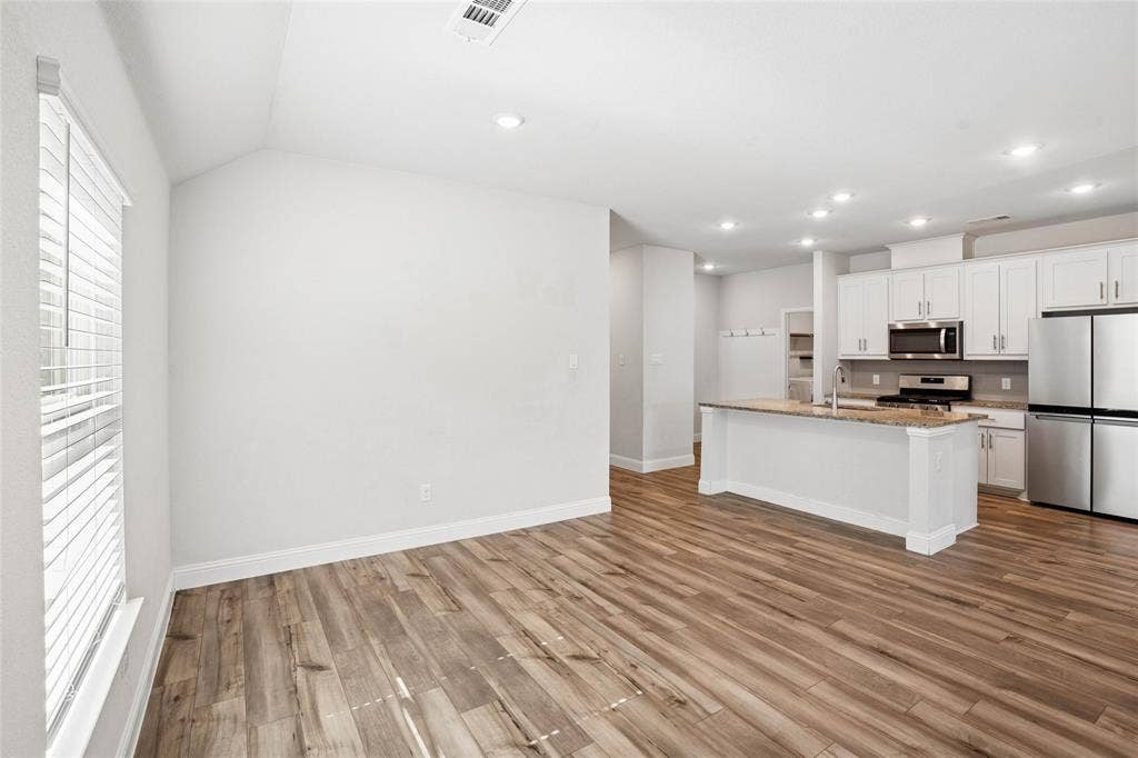 317 Fire Rock Drive, Royse City, TX 75189 Open-concept living space featuring wood-finish flooring, recessed lighting, and a vaulted ceiling