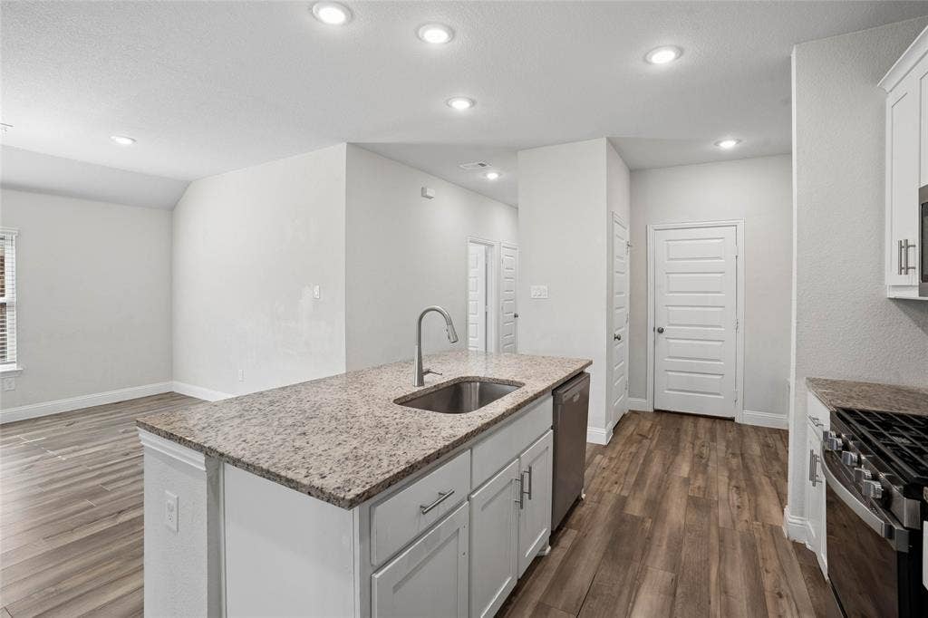 317 Fire Rock Drive, Royse City, TX 75189 Kitchen island featuring a stainless steel sink with a gooseneck faucet, light granite countertop, and white cabinetry