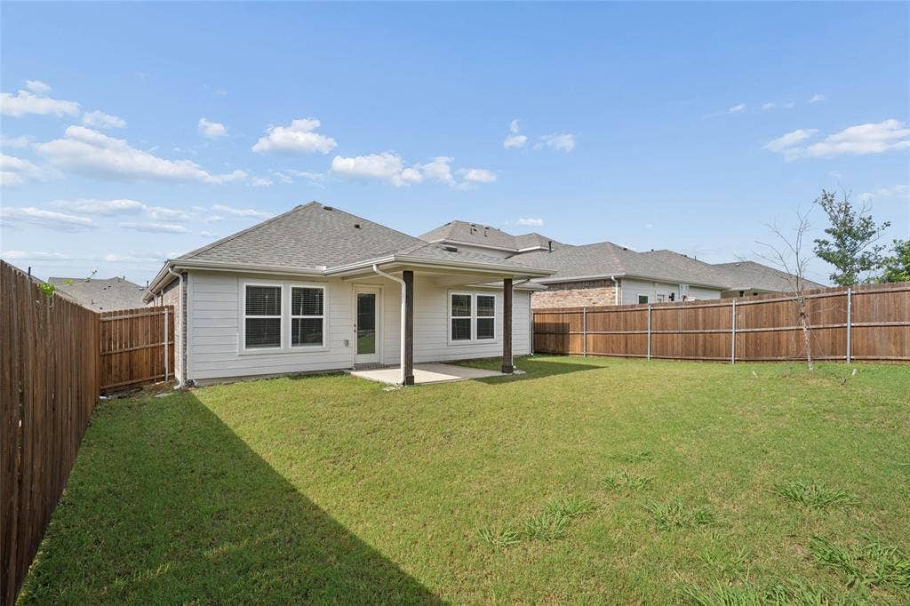 317 Fire Rock Drive, Royse City, TX 75189 Spacious backyard featuring a covered patio, privacy fencing, a manicured lawn, and exterior siding with multiple windows