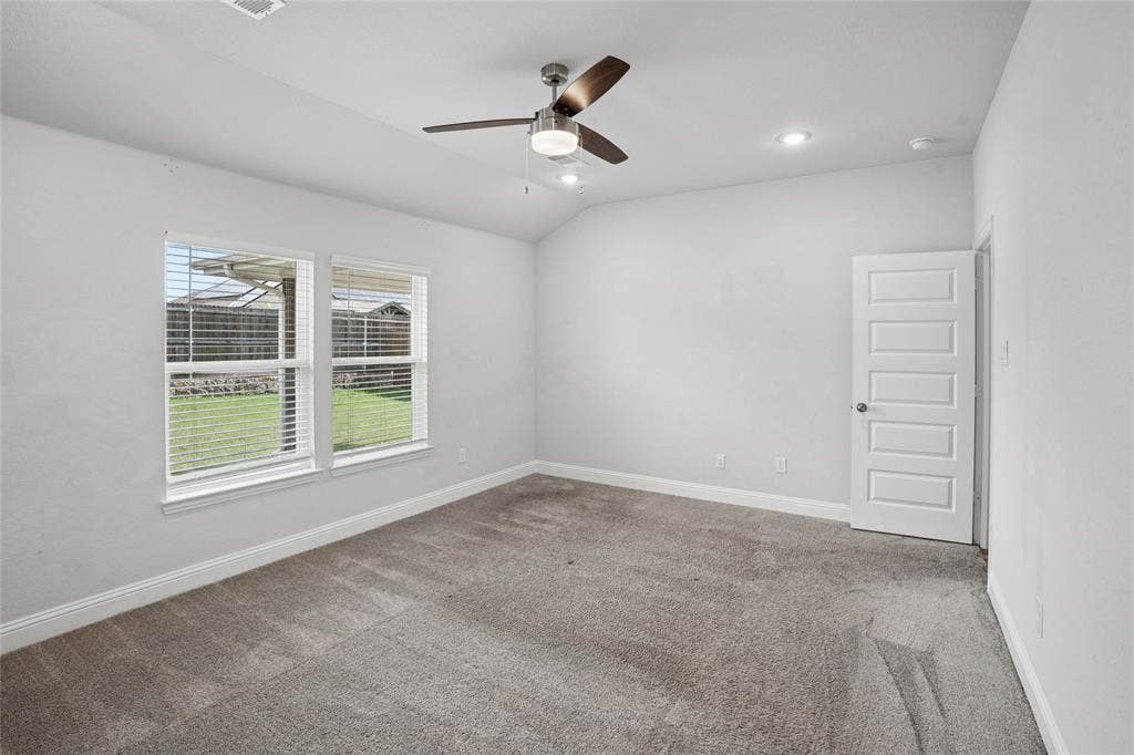 317 Fire Rock Drive, Royse City, TX 75189 Carpeted room featuring dual windows with blinds, a five-panel interior door, a ceiling fan with integrated lighting, and recessed ceiling lights