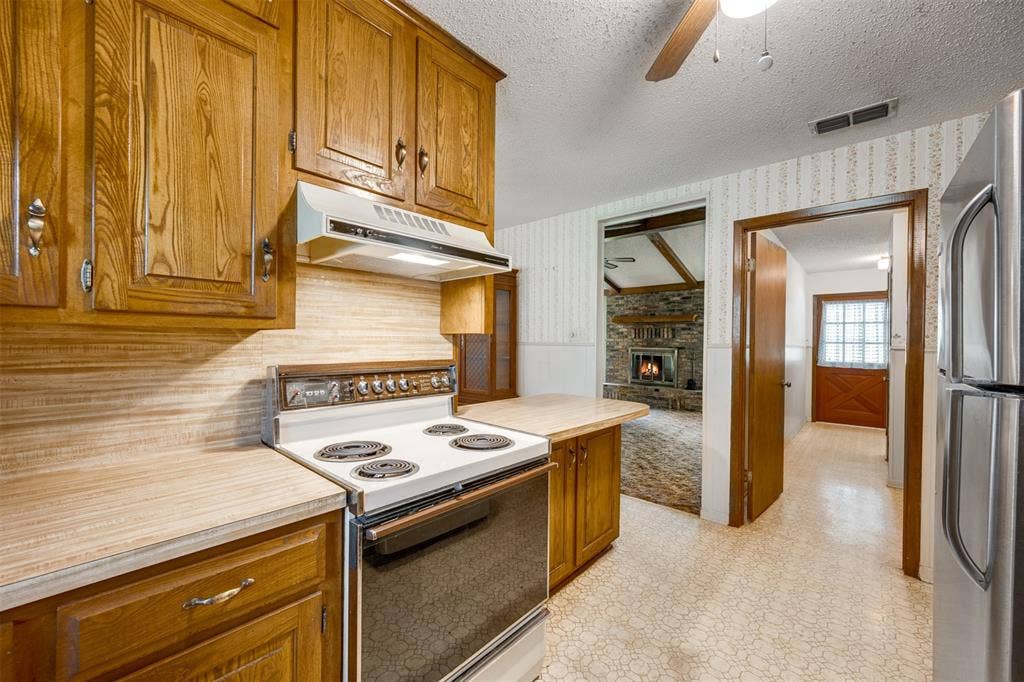 8798 Hill N Dale Road, Tyler, TX 75709 Kitchen featuring wood cabinetry, laminate countertops, and a built-in range with overhead vent hood