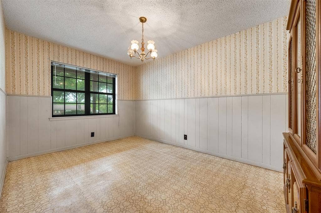 8798 Hill N Dale Road, Tyler, TX 75709 Room featuring a large window with black framing, textured wallpaper, white wainscoting, and a central brass chandelier