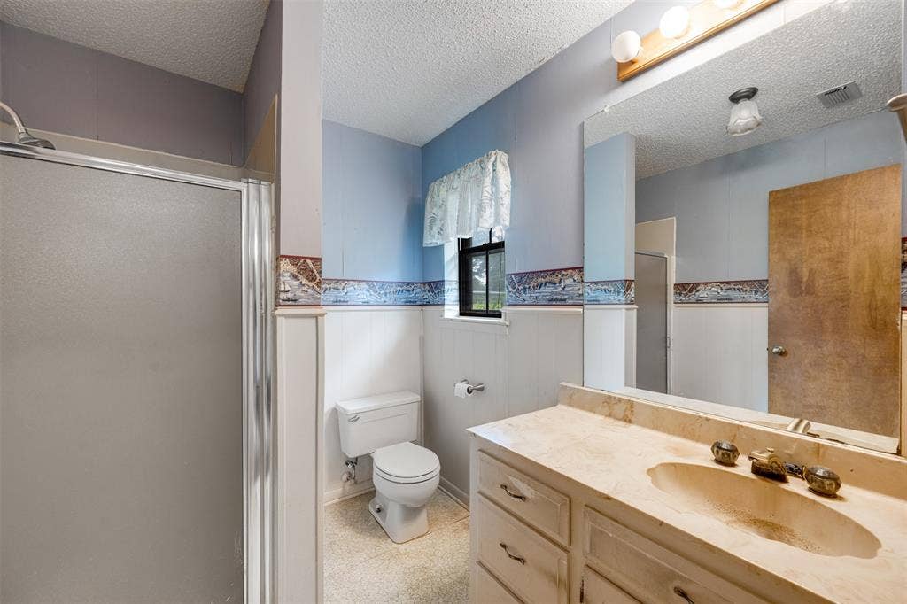 8798 Hill N Dale Road, Tyler, TX 75709 Bathroom featuring a shower with a frosted glass enclosure, a vanity with an integrated sink and light-colored countertop, and a built-in toilet