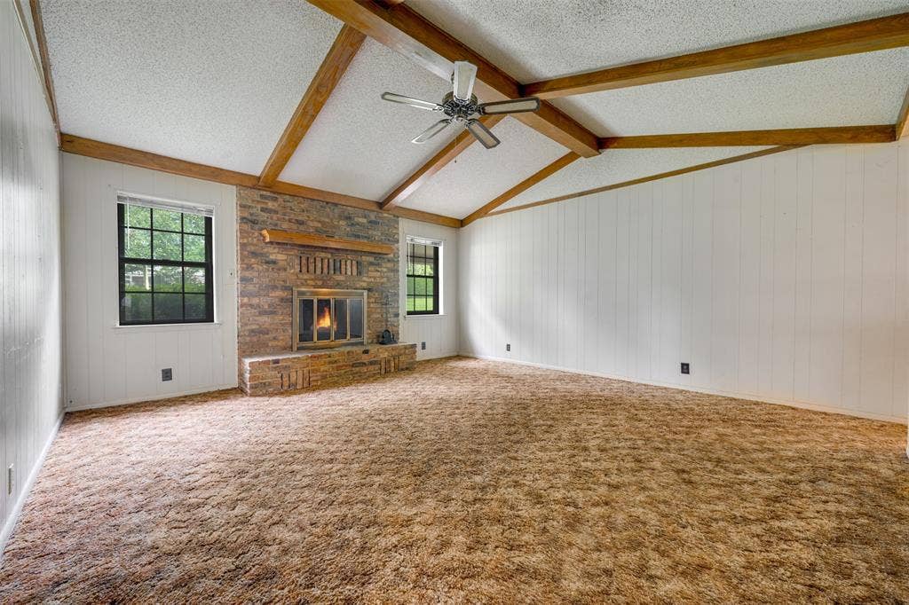 8798 Hill N Dale Road, Tyler, TX 75709 Spacious interior with vaulted ceilings, exposed wood beams, and a prominent brick fireplace with a wood mantle