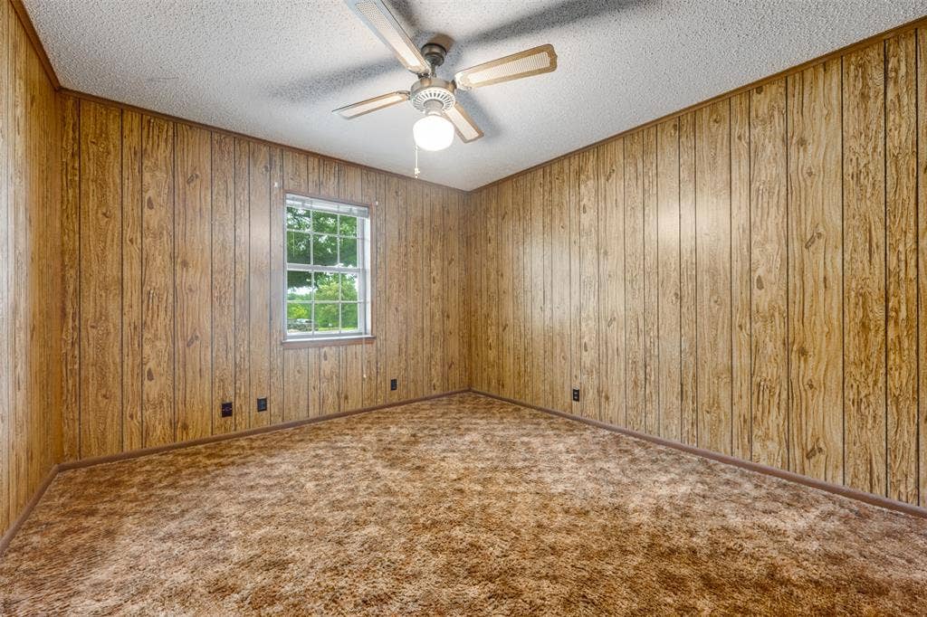 8798 Hill N Dale Road, Tyler, TX 75709 Room featuring wood-paneled walls, a single-pane window, and a ceiling fan with integrated lighting