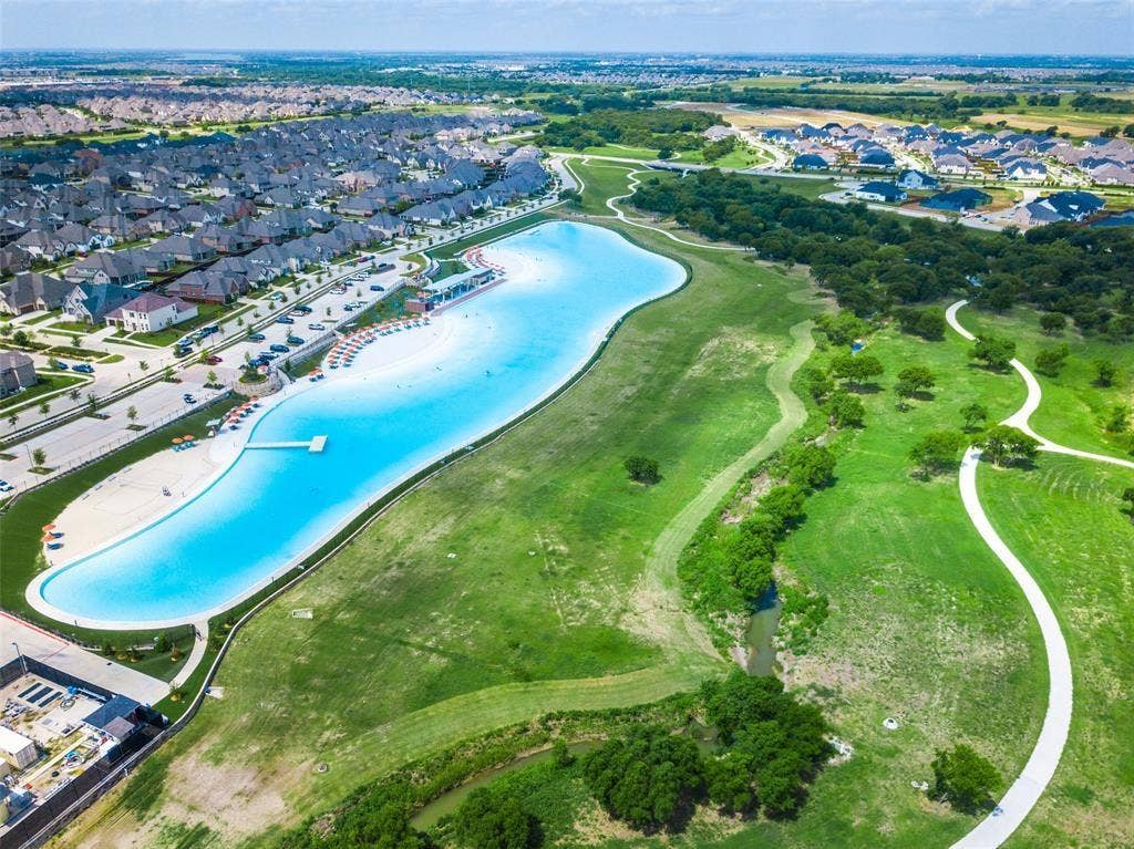 3930 Dalea Drive, Prosper, TX 75078 Expansive community lagoon with a white sand beach, surrounding walking paths, mature trees, and residential properties