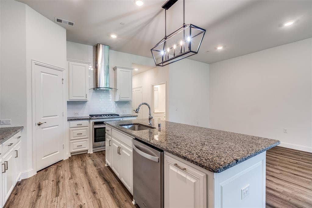 3930 Dalea Drive, Prosper, TX 75078 Modern kitchen featuring white shaker cabinetry, speckled countertops, stainless steel appliances, and wood-finish flooring