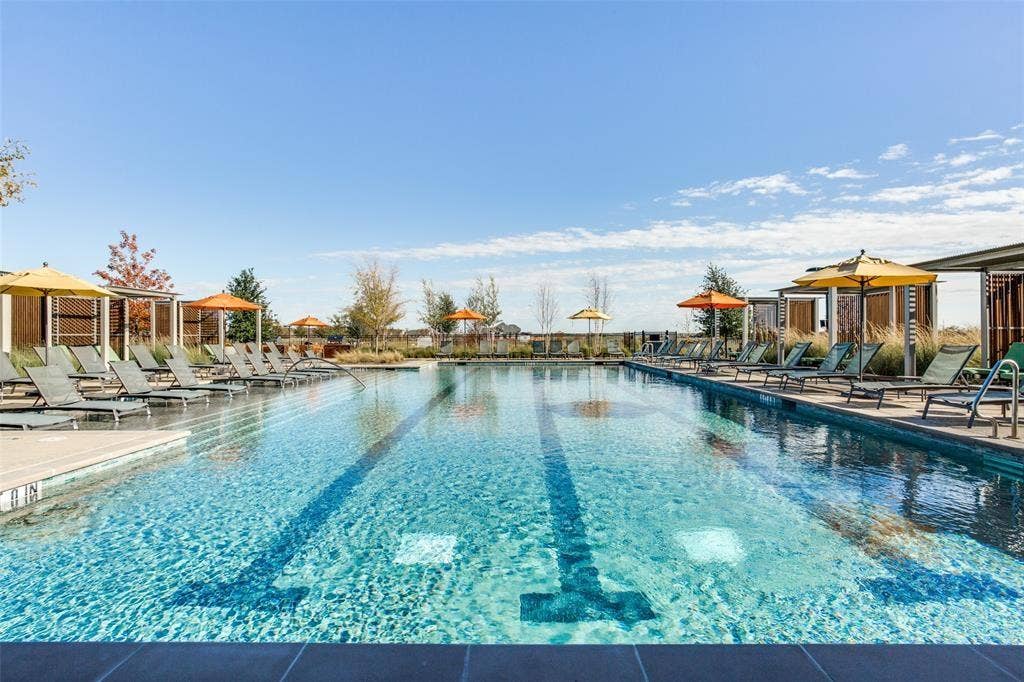 3930 Dalea Drive, Prosper, TX 75078 Resort-style aquatic amenity featuring a lap pool with lane markers, integrated lounge seating, multiple shaded areas with umbrellas, and perimeter landscaping